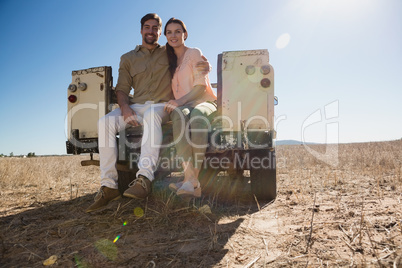 Full length portrait of couple sitting in off road vehicle on landscape