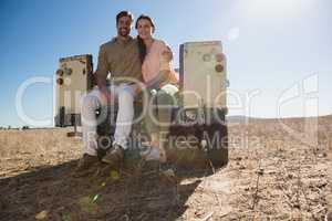 Full length portrait of couple sitting in off road vehicle on landscape
