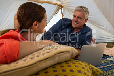 Smiling man with woman using laptop in tent