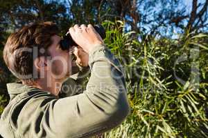 Young man looking through binocular