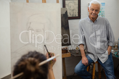 Senior man watching while artist drawing on canvas