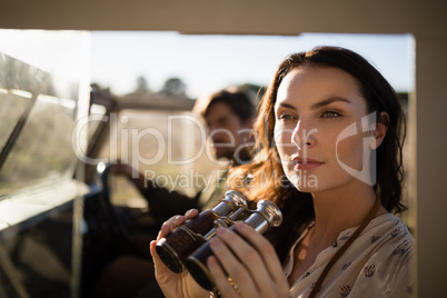 Thoughtful woman sitting with binoculars in vehicle