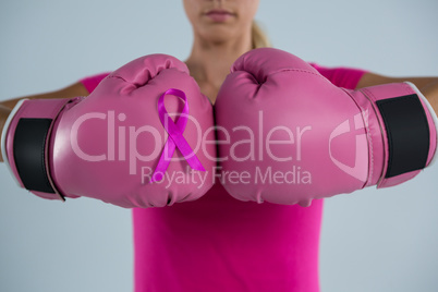 Mid section of woman with boxing gloves and pink ribbon