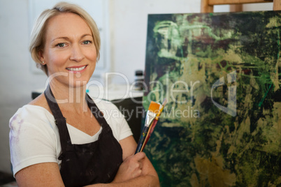 Portrait of confident woman standing with paintbrush