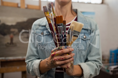 Woman holding various brushes in drawing class