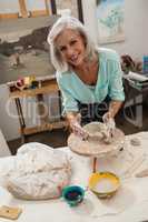 Portrait of smiling senior woman molding clay