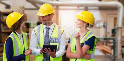 Composite image of architects in reflective clothing discussing over tablet computer