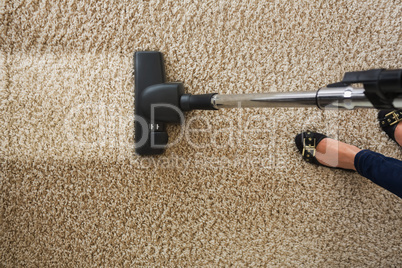 Cropped image of woman cleaning carpet with vacuum cleaner