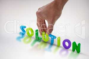 Composite image of cropped hand of businessman arranging solution word