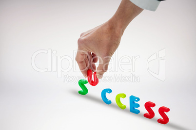 Composite image of cropped hand of businessman arranging success word