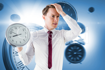 Composite image of anxious businessman holding a clock