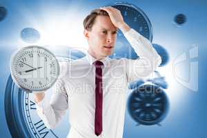 Composite image of anxious businessman holding a clock