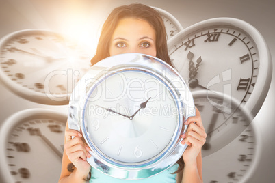 Composite image of pretty brunette holding a clock