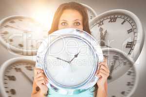 Composite image of pretty brunette holding a clock