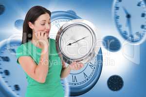 Composite image of brunette looking at wall clock