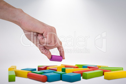 Composite image of cropped hand arranging plastic blocks