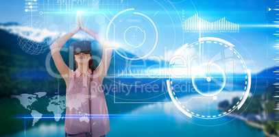 Composite image of young woman with arms raised looking through virtual reality simulator