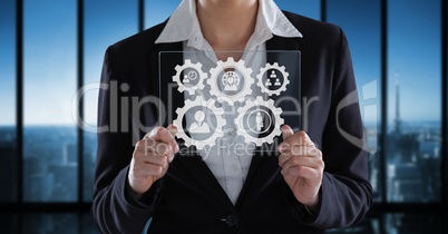 Business woman interacting with people in cogs graphics against office background