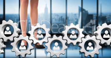 Business woman standing behind people in cogs graphics against office background