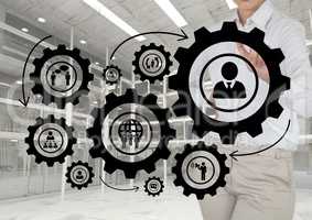 Business woman interacting with people in cogs graphics against office background