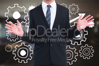 Business man standing against people in cogs graphics against office background
