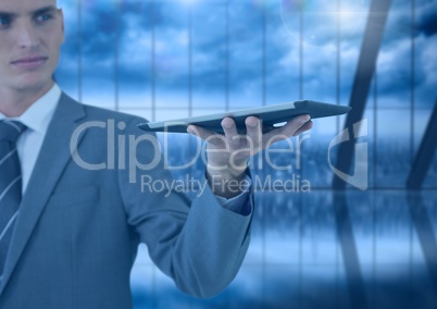 Businessman holding tablet with dark windows over city