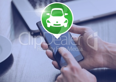 Hand holding phone with car icon at desk