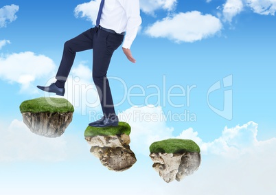 Businessman walking up steps of floating rock platforms in sky