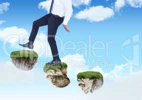 Businessman walking up steps of floating rock platforms in sky