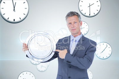 Business man holding a clock against background with clocks