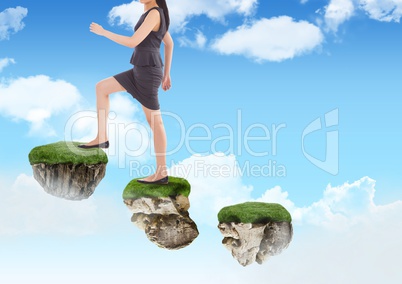 Businesswoman walking up steps of floating rock platforms in sky