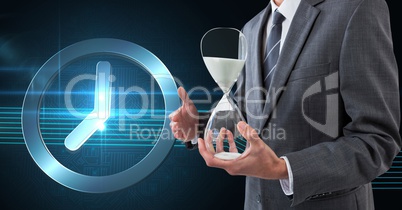 Business man holding a sand clock against background with clock