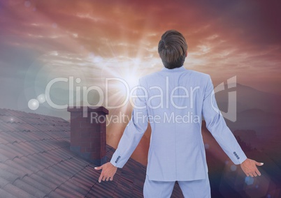 Businessman standing on Roof with chimney and epic twilight sunset