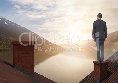 Businessman standing on Roofs with chimney and lake mountain landscape