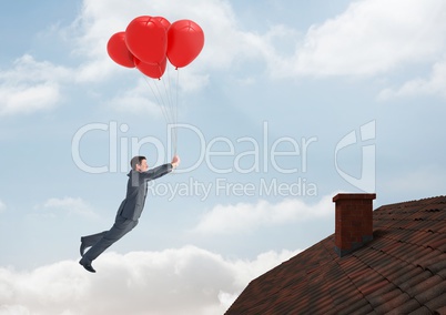 Businessman floating with balloons by Roof with chimney and blue sky