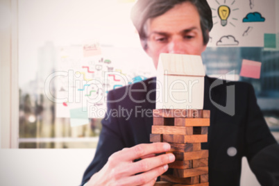 Composite image of businessman arranging wooden blocks at table