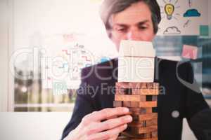 Composite image of businessman arranging wooden blocks at table
