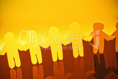 Yellow paper cut out figures making chain on glass table