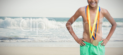 Composite image of cheerful swimmer boy wearing medals