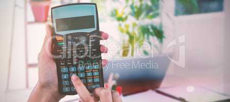 Composite image of hands of businesswoman using calculator