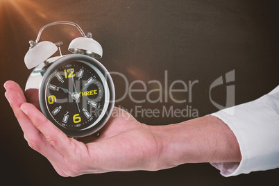 Composite image of cropped hand of male executive holding alarm clock