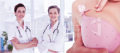 Composite image of mid section of woman wearing pink bra for breast cancer awareness