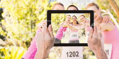 Composite image of cropped hand holding digital tablet