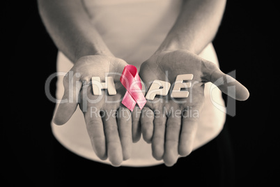 Mid section of woman holding pink ribbon with hope text