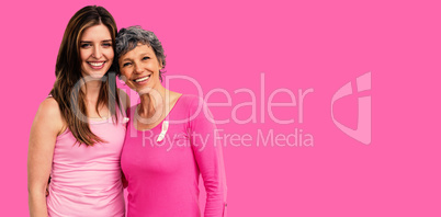 Composite image of smiling women in pink outfits posing for breast cancer awareness