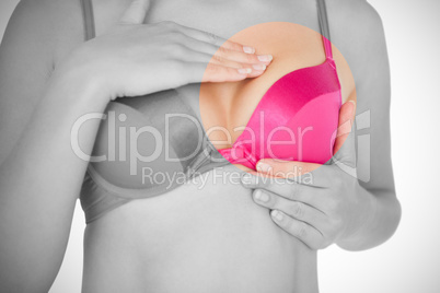 Mid section of woman in pink bra checking breast for cancer awareness