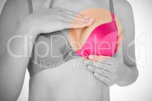 Mid section of woman in pink bra checking breast for cancer awareness