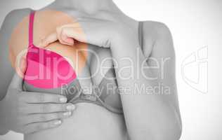 Mid section of woman in pink bra touching breast for cancer awareness