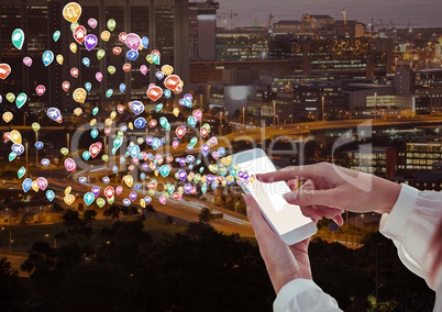 woman hands with phone with application icons coming up form it. Blurred city at night