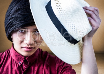 Close up of millennial man tipping hat against brown room